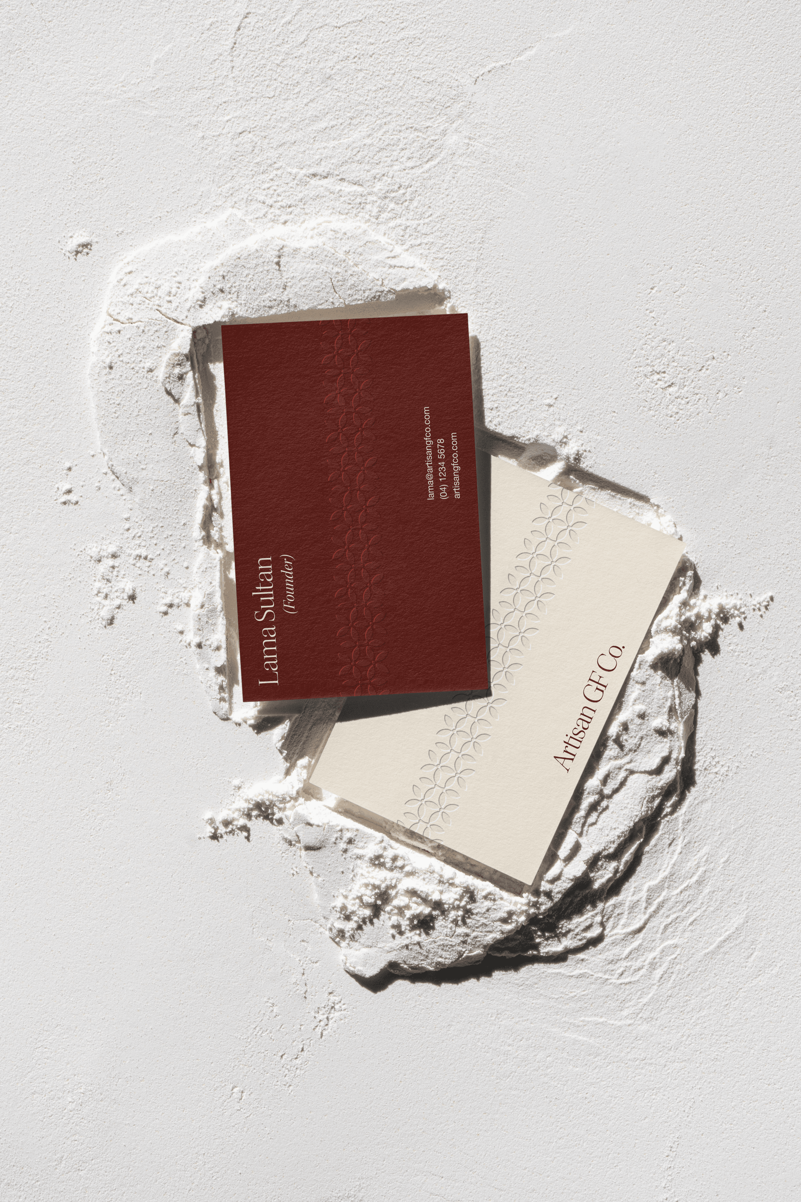 Berry and cream Artisan GF Co. business cards pressed into a drift of flour